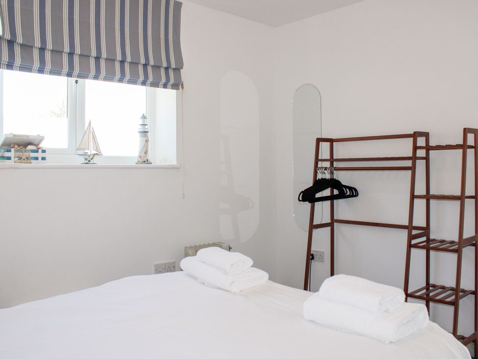 A bedroom with towels on the bed and a shelf with decorative items at Gilly's Cottage in Hope Cove