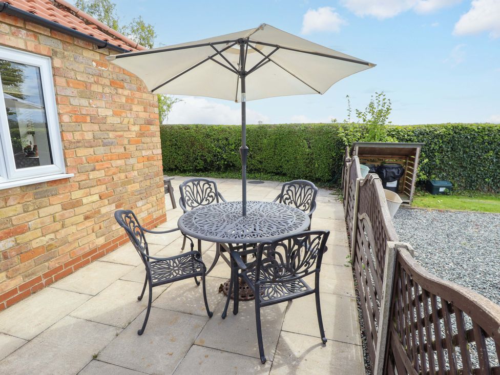 A patio with a table and chairs under an umbrella at The New Build in South Reston near Louth