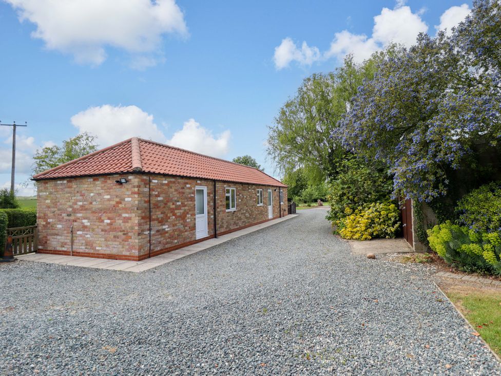 A house with a gravel driveway and surrounding trees at The New Build in South Reston near Louth