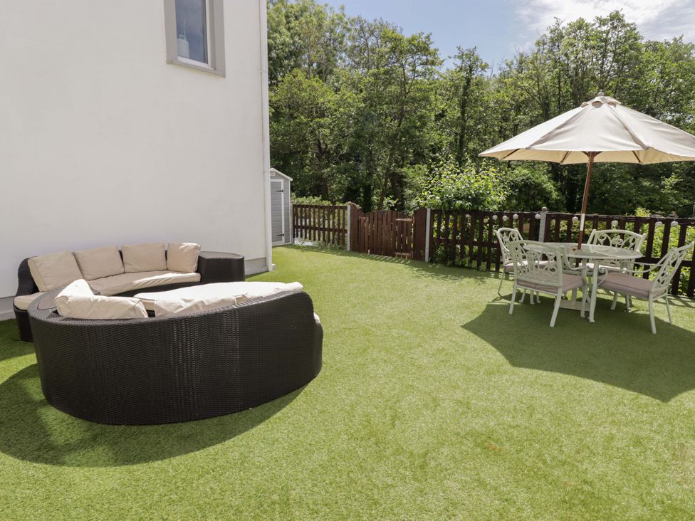 A garden with an outdoor sofa and a dining set at Charlecote House in Saundersfoot
