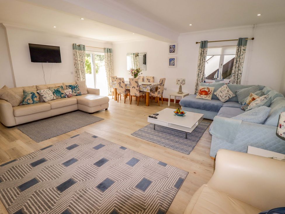 A living room with a sofa, coffee table, and dining area at Charlecote House in Saundersfoot