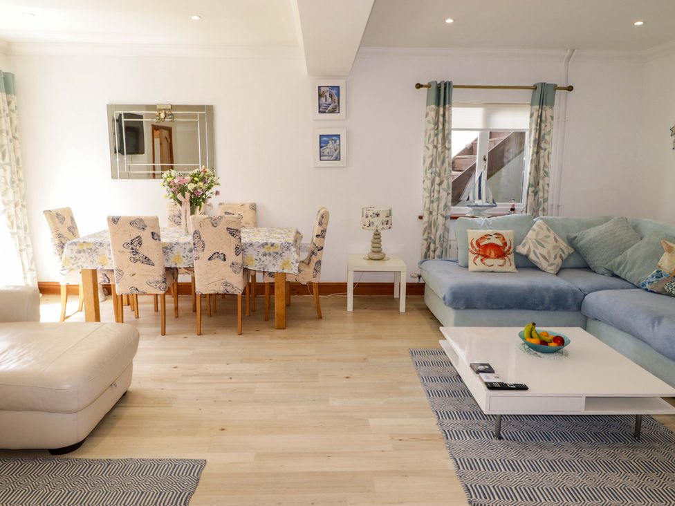 A living room with a sofa and dining area at Charlecote House in Saundersfoot