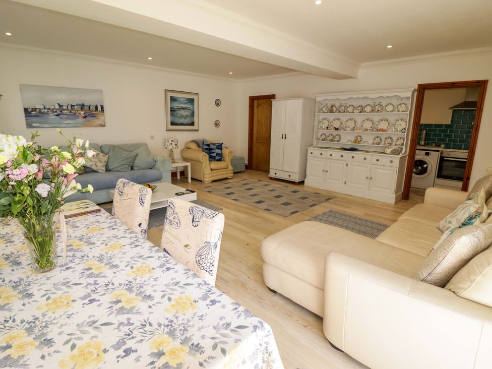 A living room with a table, chairs, and a sofa at Charlecote House in Saundersfoot