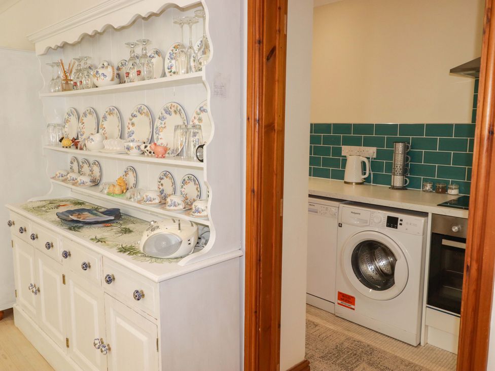A kitchen with a shelf displaying dishes and appliances at Charlecote House in Saundersfoot