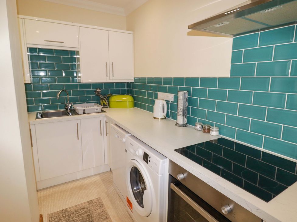 A kitchen with sink and washing machine at Charlecote House in Saundersfoot