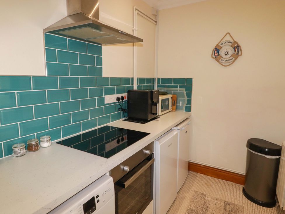 A kitchen with appliances and teal tiles at Charlecote House in Saundersfoot