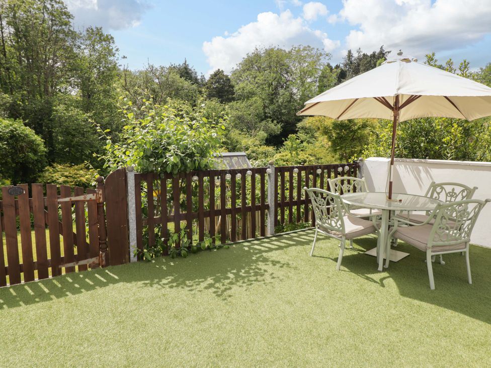 A garden with a table and chairs under an umbrella at Charlecote House in Saundersfoot