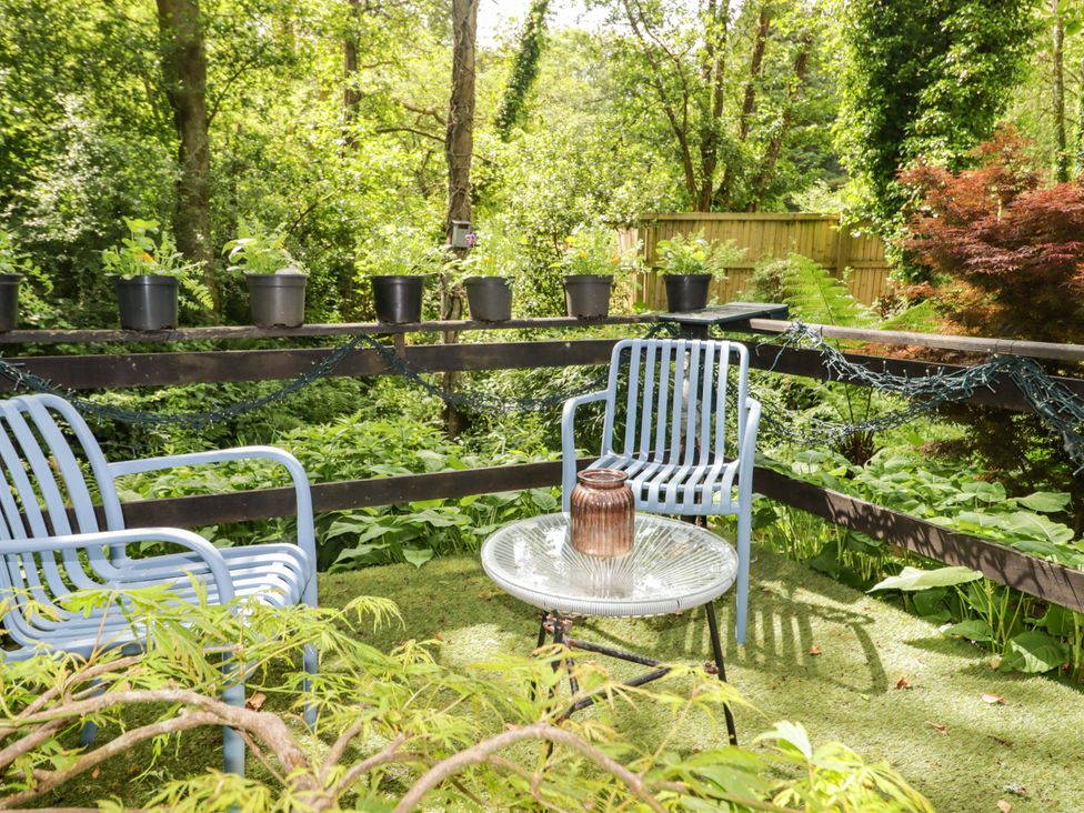 A garden with chairs, a table and potted plants at Charlecote House in Saundersfoot