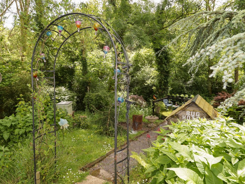A garden with an arch and bug hotel at Charlecote House Saundersfoot