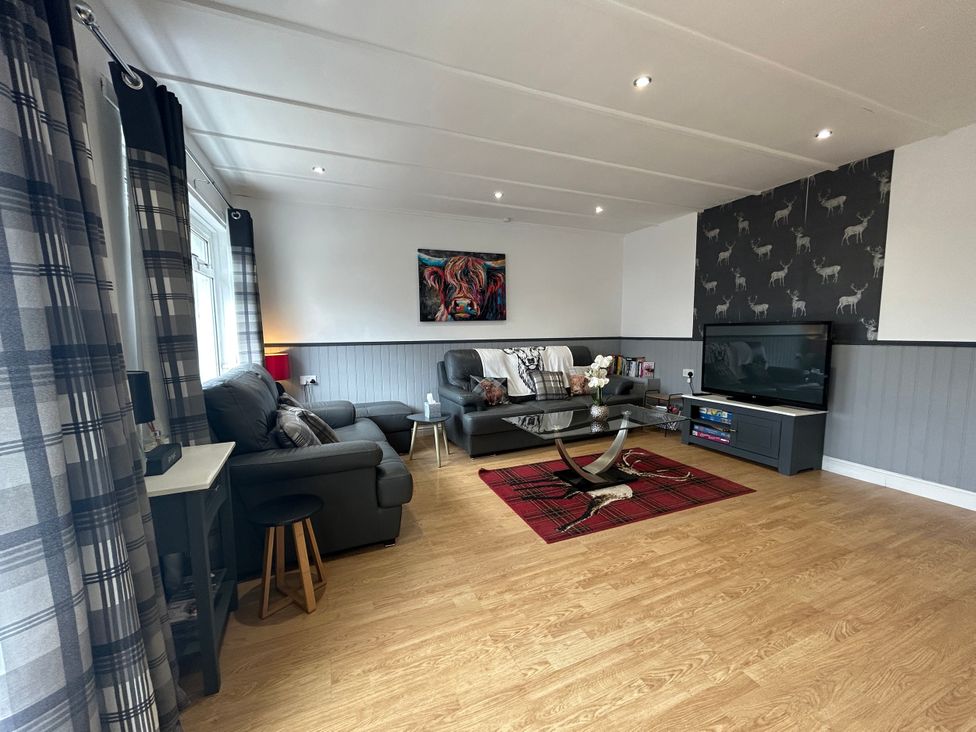 A living room with a sofa, coffee table, and TV at Solway Cottage in Powfoot near Annan