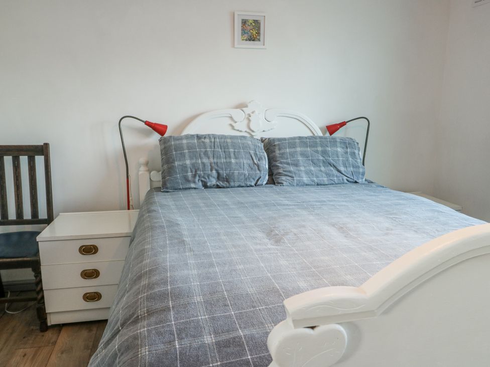 A bedroom with a bed and bedside lamp at 7 Bro Branwen near Rhosneigr