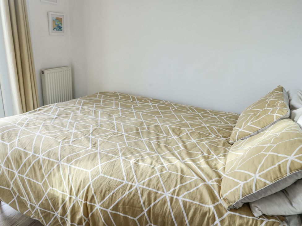 A bedroom with a bed covered in patterned bedding at 7 Bro Branwen Aberffraw near Rhosneigr