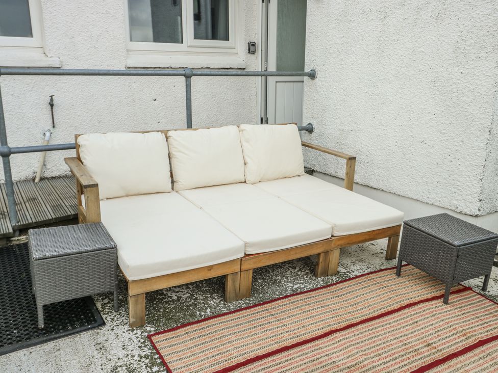 A sofa with cushions and a side table on a patio area at 7 Bro Branwen Aberffraw near Rhosneigr