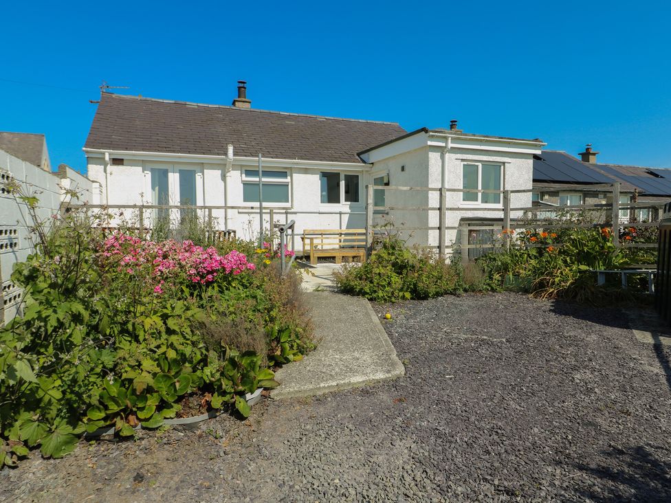 A house with garden flowers and a pathway at 7 Bro Branwen Aberffraw near Rhosneigr