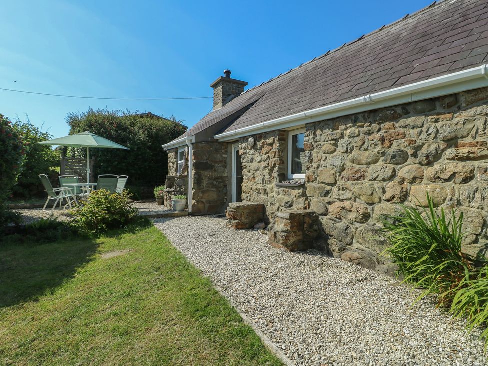An outdoor area with a stone cottage and seating at Sunstone (Garreg Haul) Cilan near Abersoch