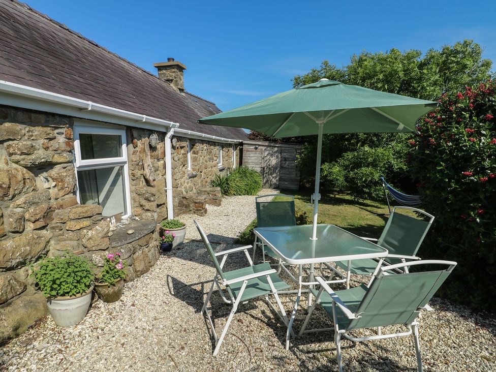 A garden with a table and chairs under a parasol at Sunstone (Garreg Haul) Cilan near Abersoch