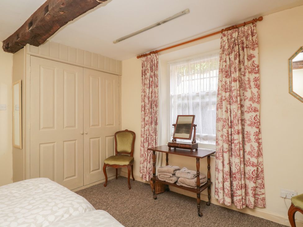 A bedroom with a wardrobe, chair, table, and mirror at Dollar Ward House Basement Cirencester