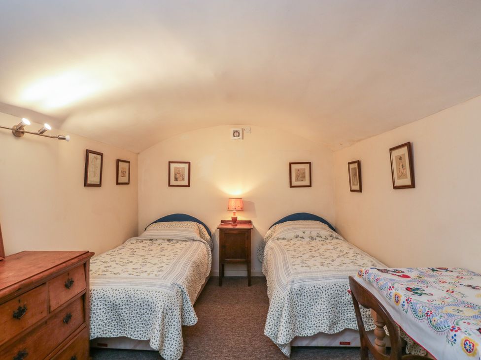 A bedroom with two beds and a bedside table at Dollar Ward House Basement in Cirencester