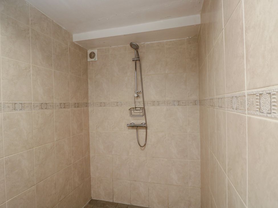 A bathroom with a shower and tiled walls at Dollar Ward House Basement Cirencester