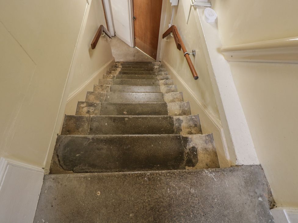 Stairs with a handrail leading to a door at Dollar Ward House Basement Cirencester