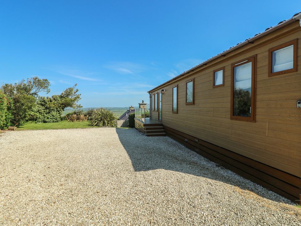 An outdoor area with a lodge and trees at Sunstone Lodge (Garreg Haul Lodge) Cilan near Abersoch