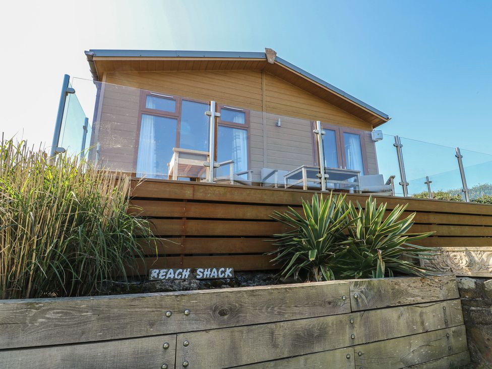 A lodge with a balcony and a wooden deck at Sunstone Lodge (Garreg Haul Lodge) Cilan near Abersoch