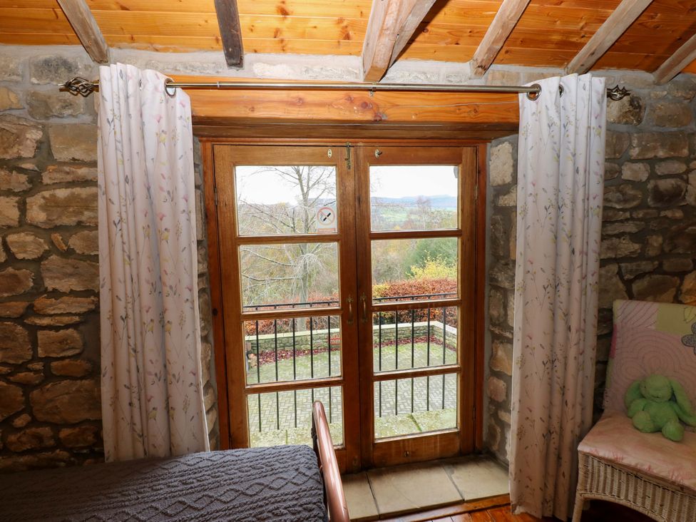A bedroom with stone walls and double doors leading to the outside at The Granary in Rothbury