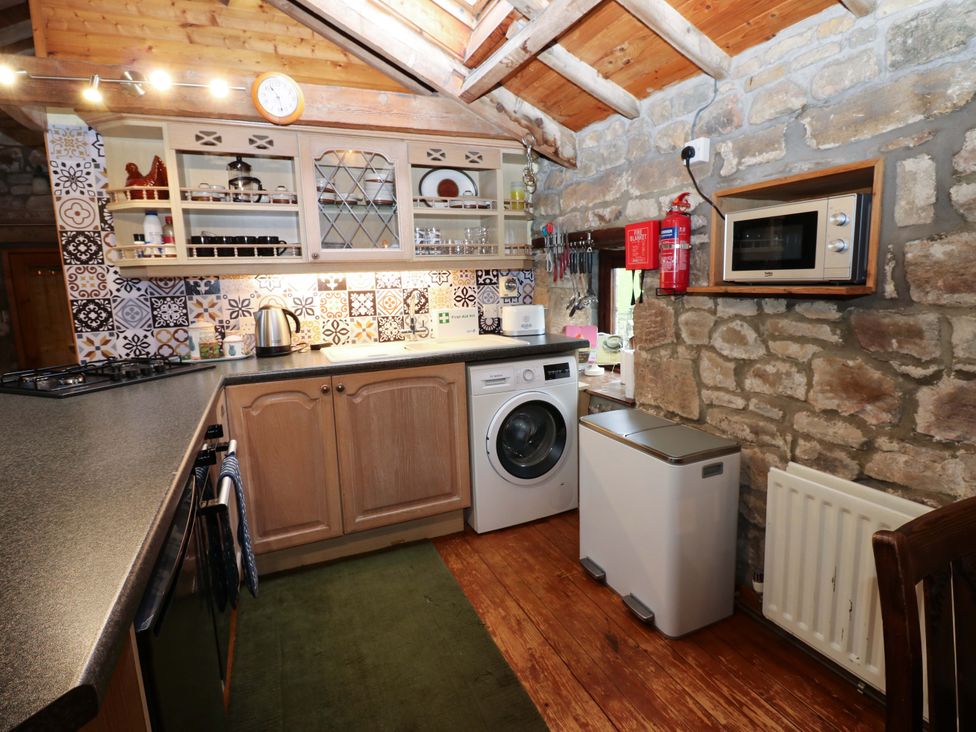 A kitchen with appliances and wooden cabinets at The Granary in Rothbury