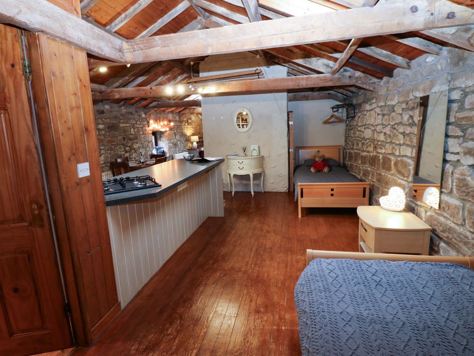A bedroom with a bed and kitchen area at The Granary in Rothbury