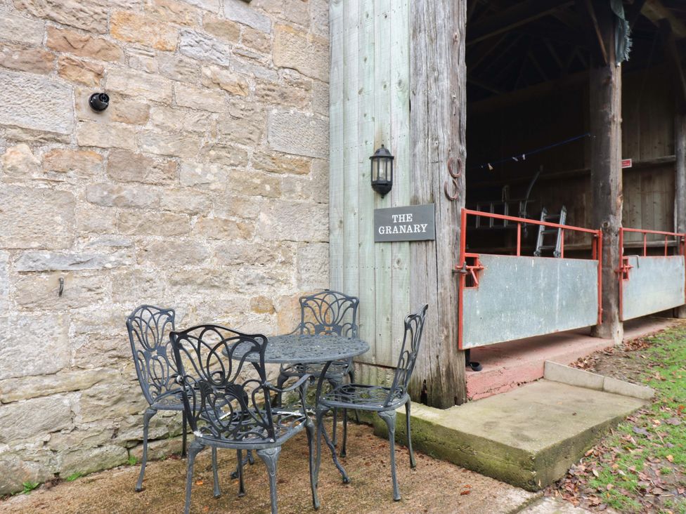 A table and chairs by a stone wall at The Granary in Rothbury