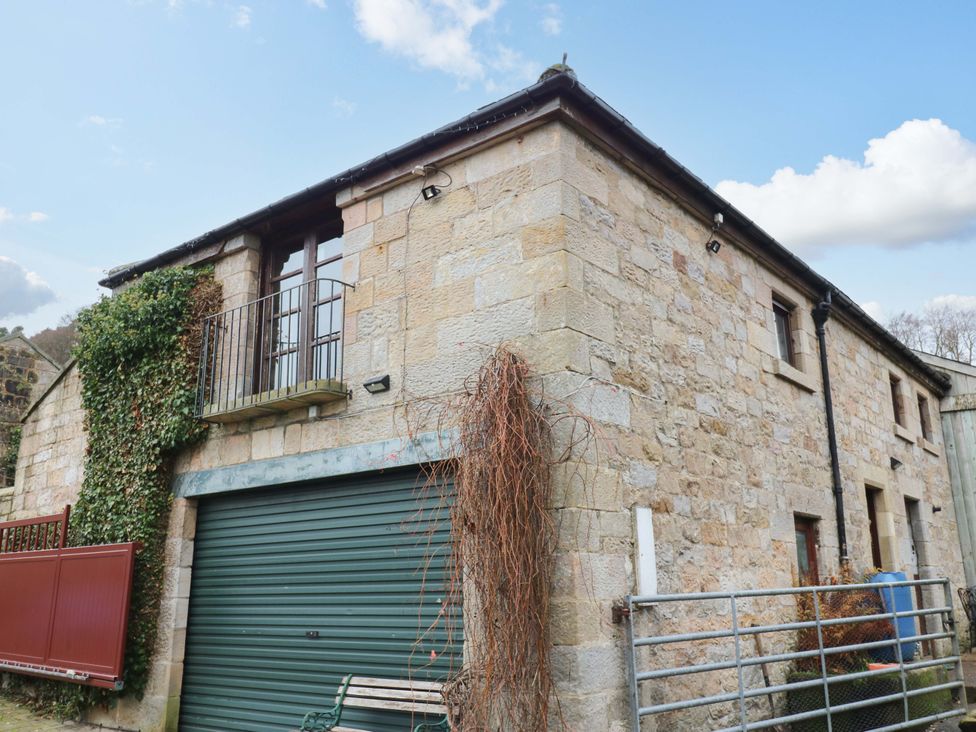 An outdoor view of a stone building with a balcony and garage at The Granary in Rothbury
