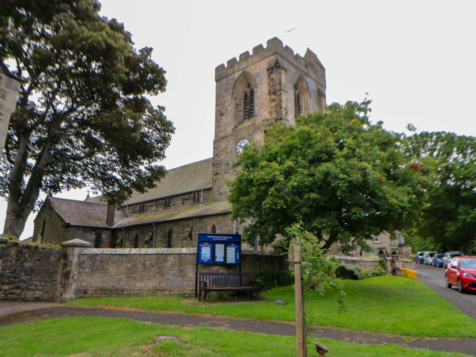 A church with clock tower and bench outside at The Granary in Rothbury