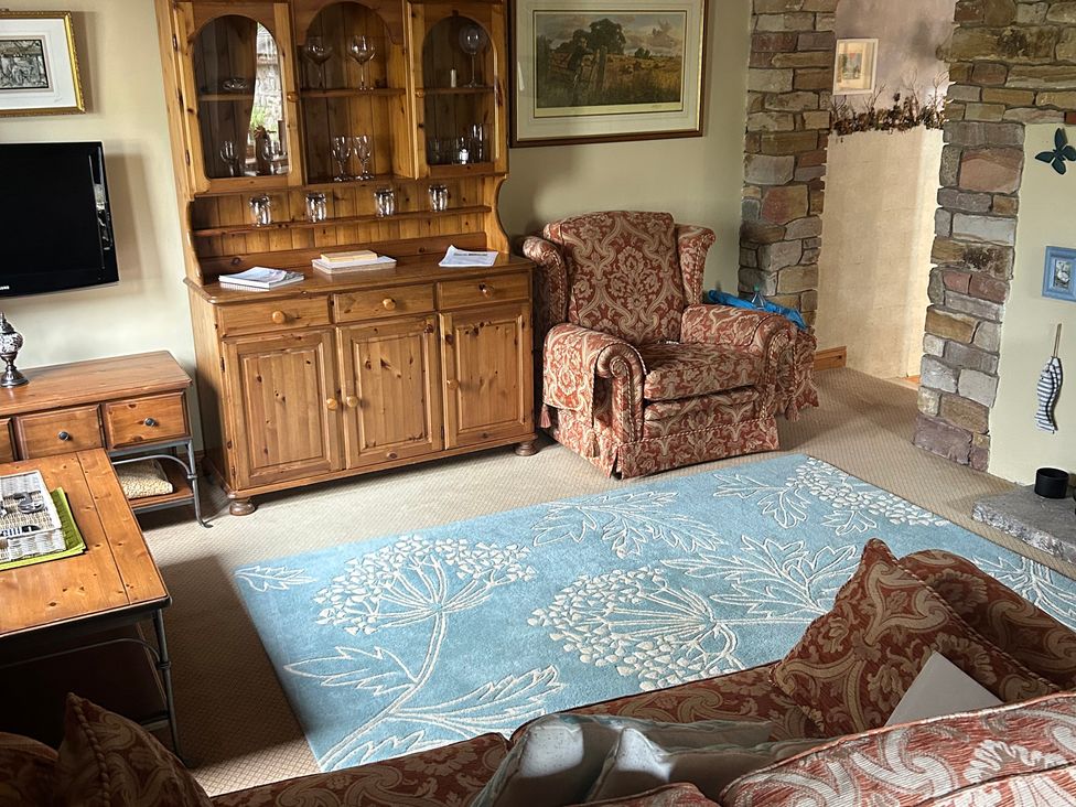 A living room with a cabinet and armchair at Swaledale Watch Garden Annexe in Caldbeck