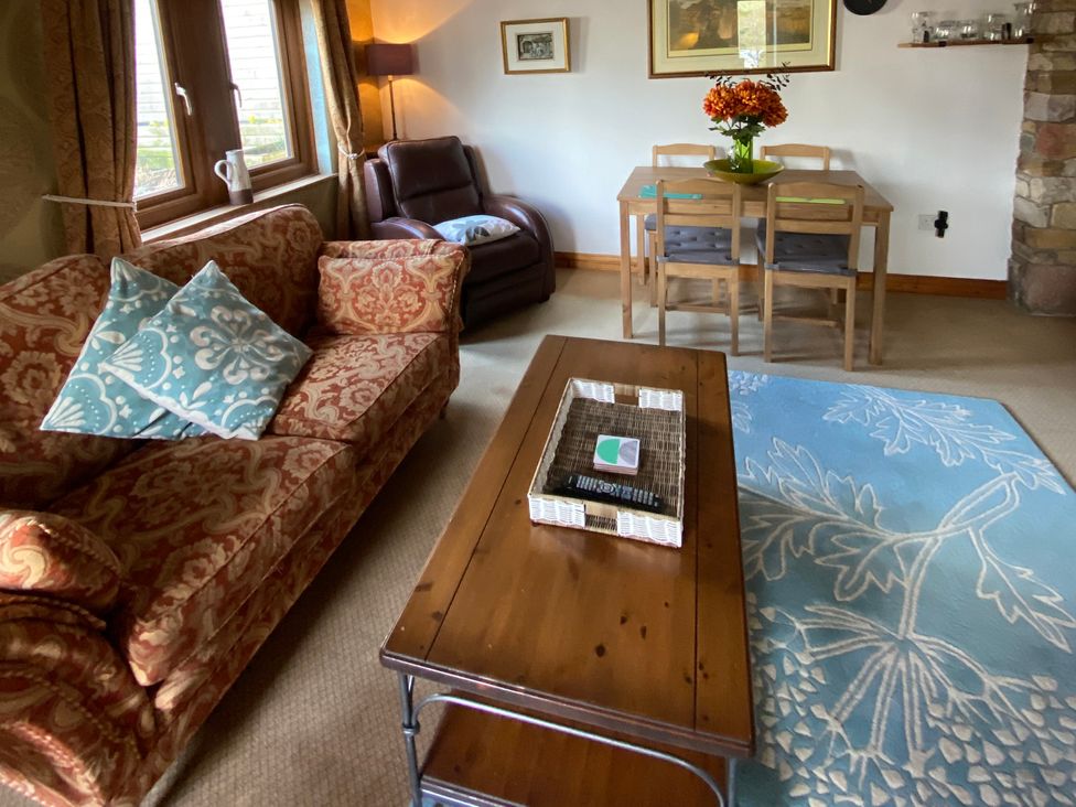 A living room with a sofa, coffee table and dining area at Swaledale Watch Garden Annexe in Caldbeck