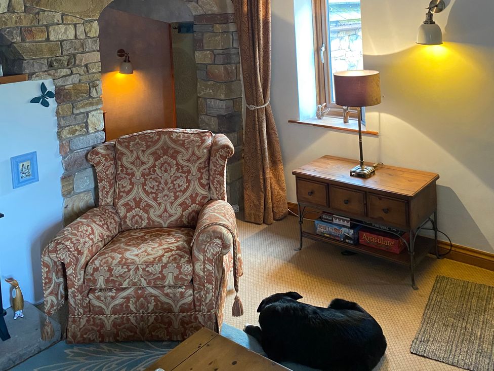 A living room with an armchair and a table lamp at Swaledale Watch Garden Annexe in Caldbeck