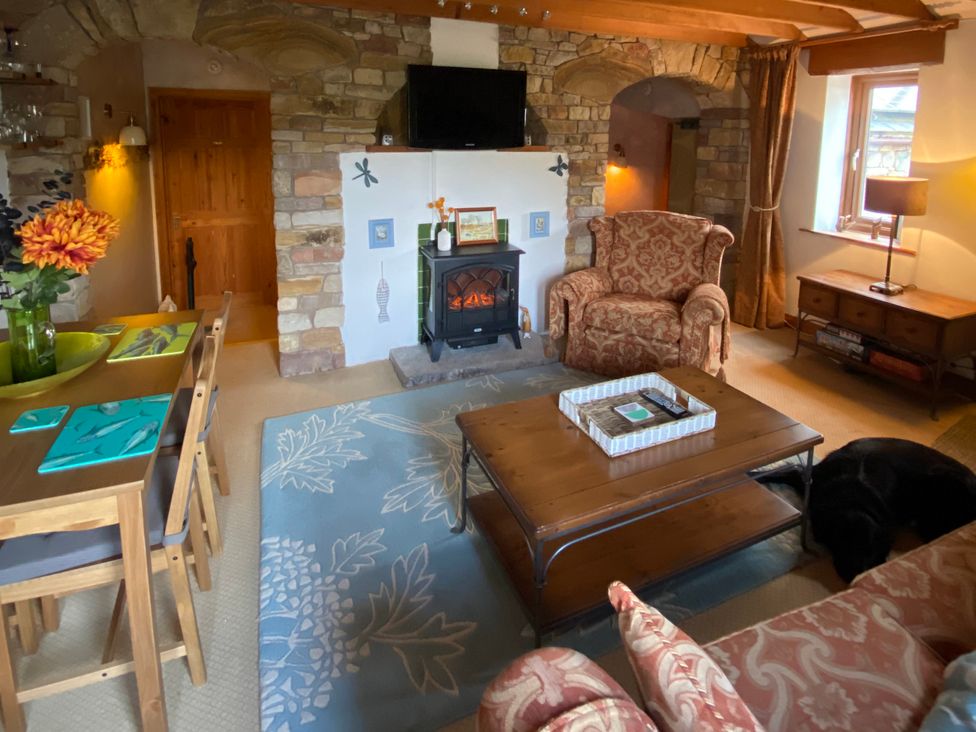 A living room with an armchair and coffee table at Swaledale Watch Garden Annexe in Caldbeck