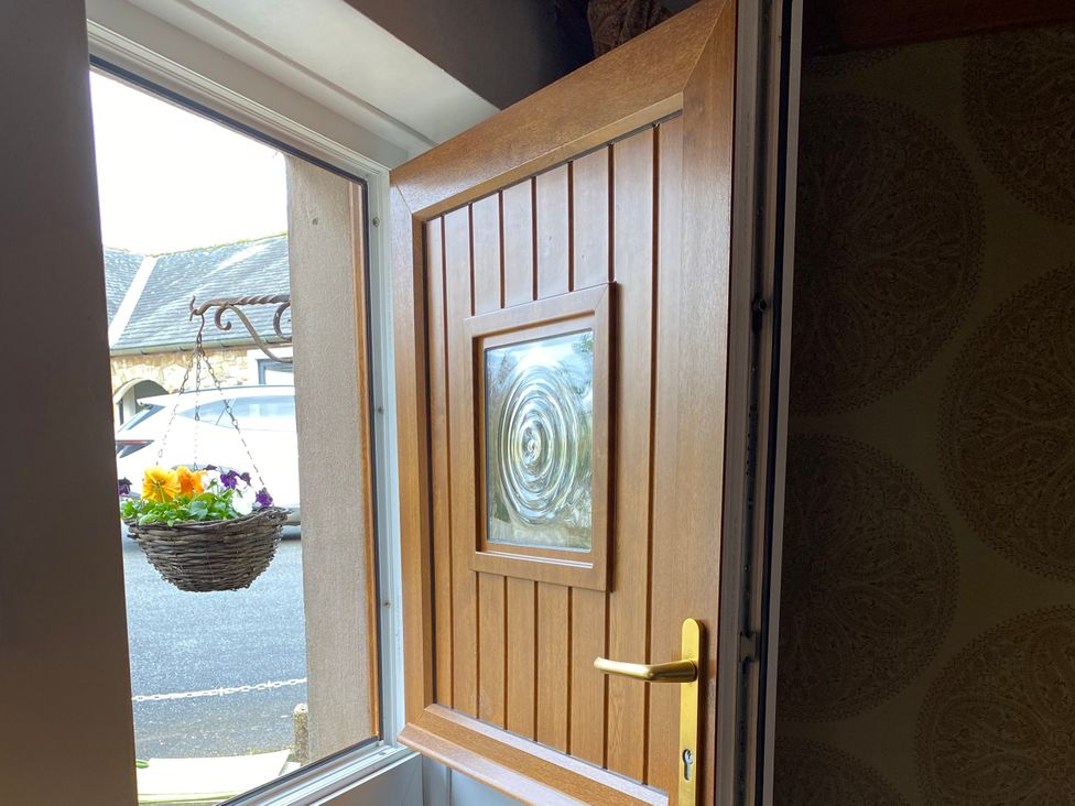 An entryway with a wooden door and a hanging basket at Swaledale Watch Garden Annexe, Caldbeck