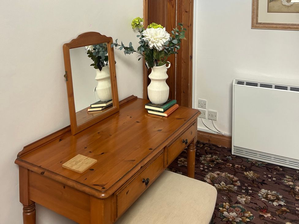 A dresser with a mirror and a vase at Swaledale Watch Garden Annexe in Caldbeck