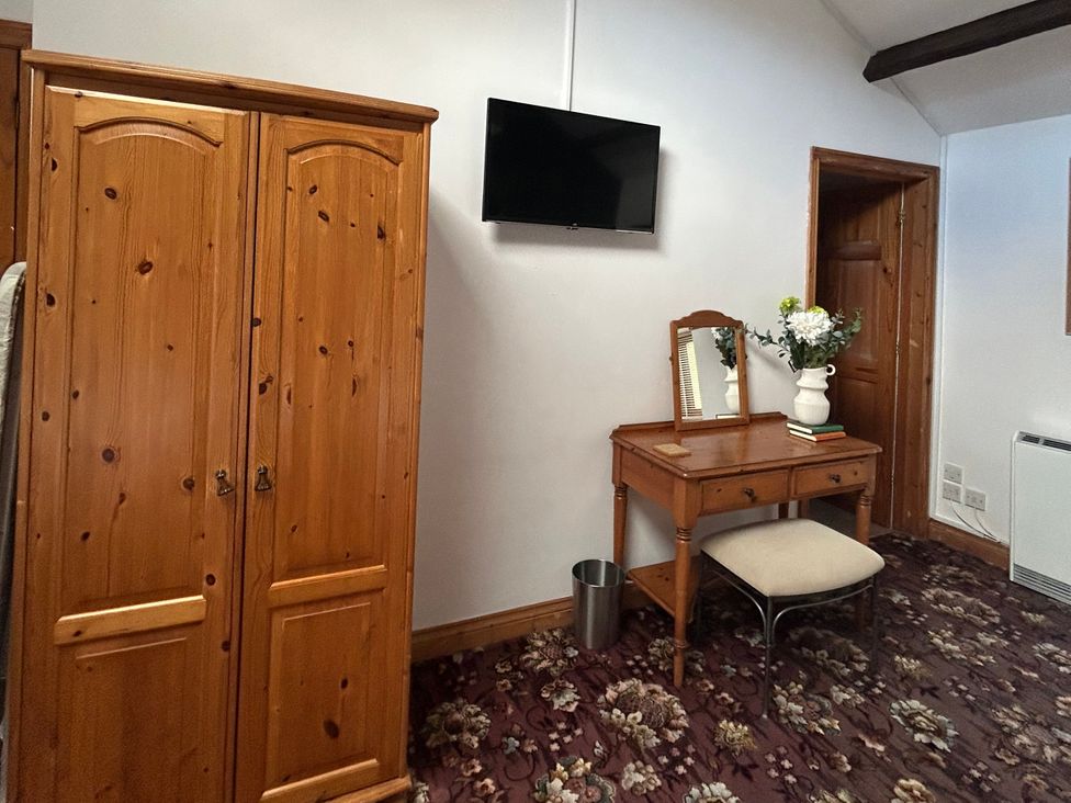 A bedroom with a wardrobe, table and chair at Swaledale Watch Garden Annexe in Caldbeck