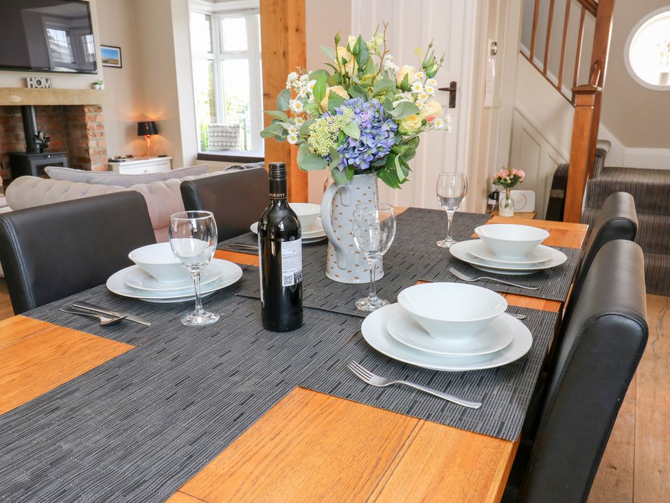 A dining room table set with dinnerware and a flower arrangement at Farnhill View, Cross Hills