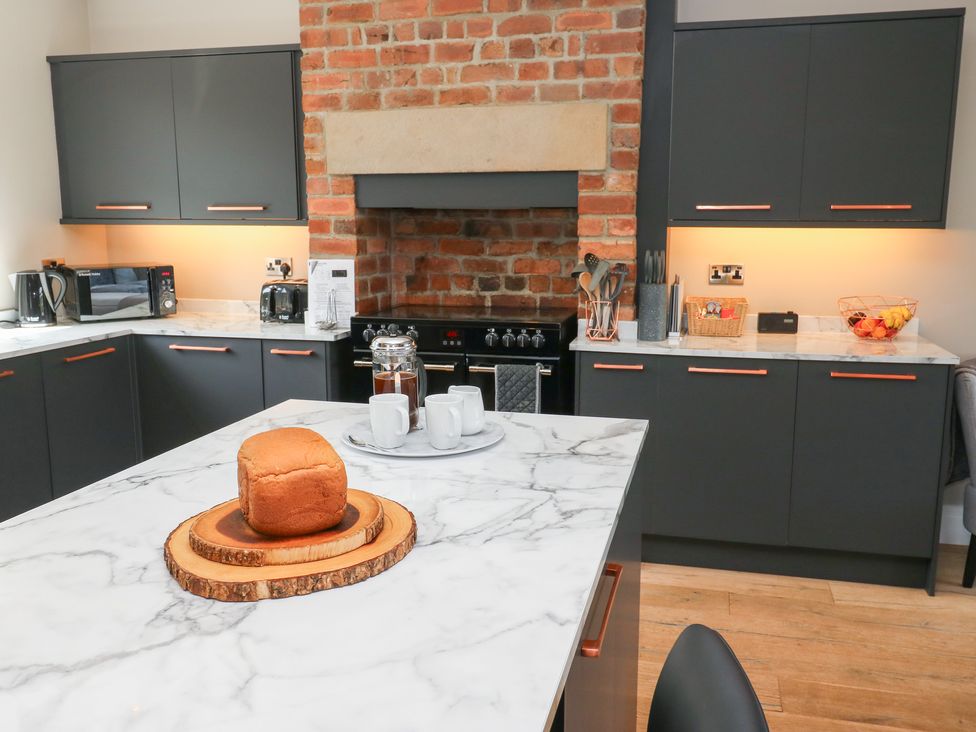 A kitchen with black cabinets and a marble countertop at Farnhill View in Cross Hills