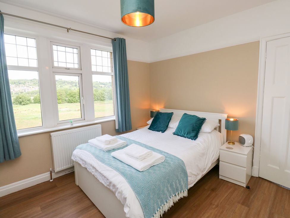 A bedroom with a bed and windows at Farnhill View in Cross Hills