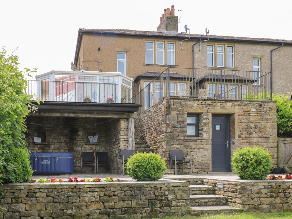 A house with a balcony and hot tub at Farnhill View Cross Hills