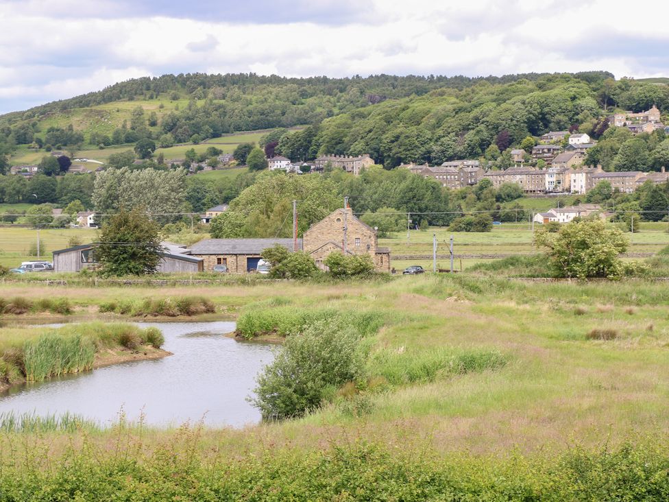 A view of hills and houses with a pond in the foreground at Farnhill View, Cross Hills