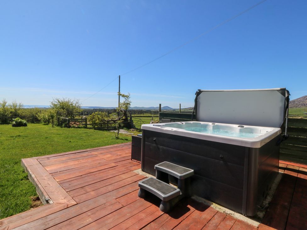 A hot tub with steps on a wooden deck at Cefnbron in Llanaelhaearn near Trefor