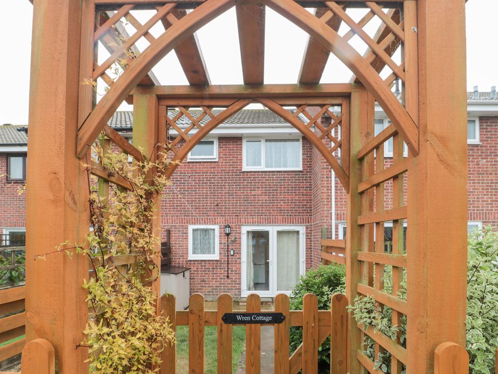An arbor leading to a door and window at Wren Cottage in Weymouth