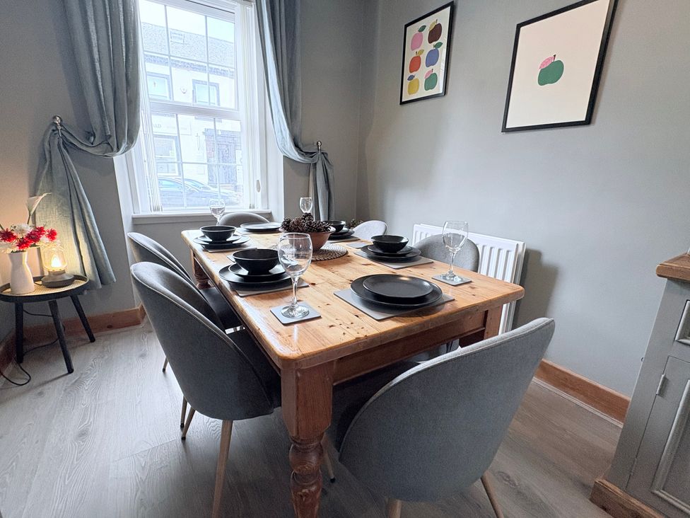 A dining room with a wooden table set for a meal at The Oaks Cottage Penrith