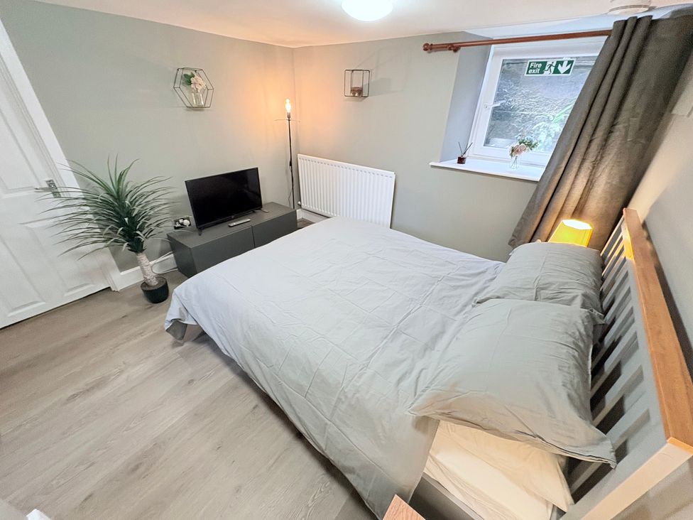 A bedroom with a bed and television at The Oaks Cottage in Penrith