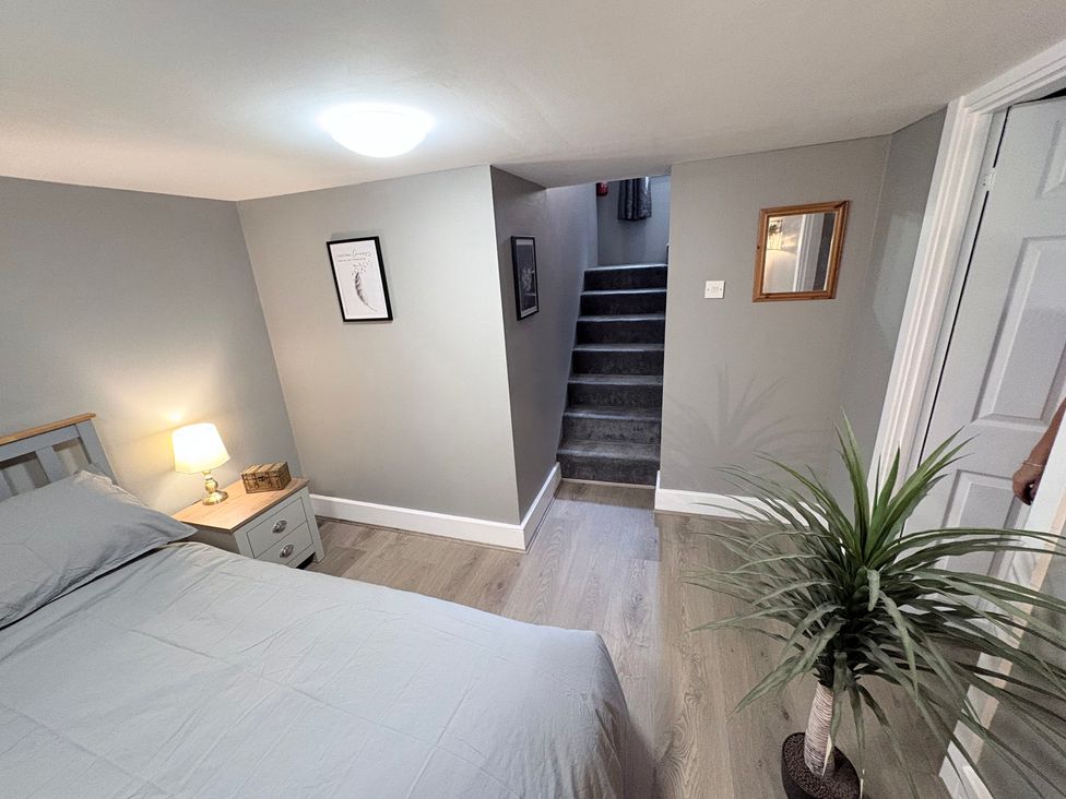A bedroom with a bed and stairs at The Oaks Cottage in Penrith