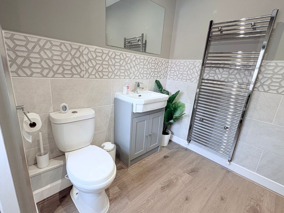 A bathroom with a toilet, sink, and towel rail at The Oaks Cottage in Penrith